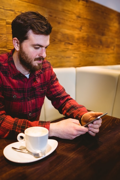 Man using mobile phone by coffee cup in restaurant