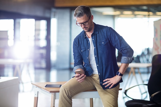 Uomo che utilizza telefono cellulare nell'ufficio