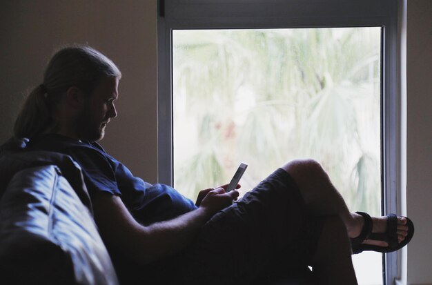 Photo man using mobile phone on sofa at home