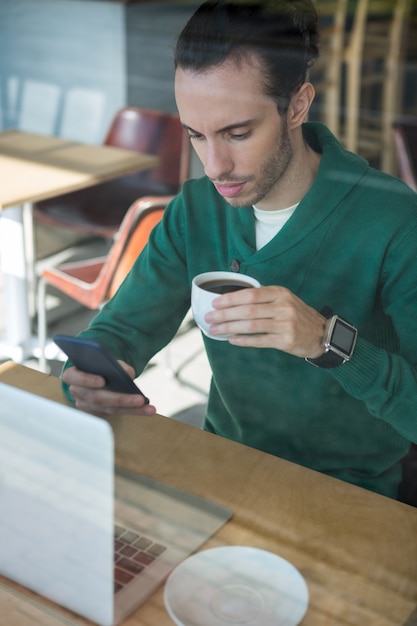 Man using mobile phone while having cup of coffee