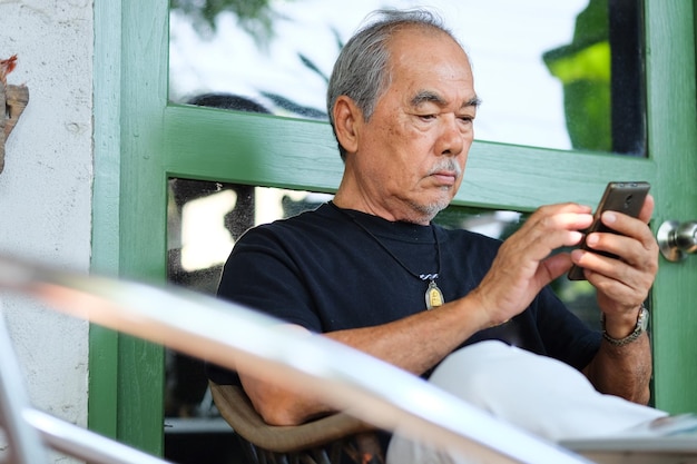 Man using mobile phone while sitting against door