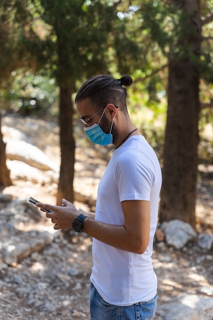 Man using mobile phone with mask and white T-shirt