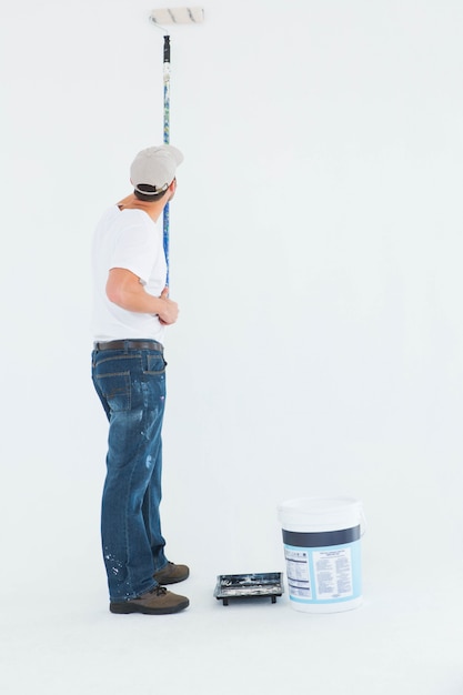 Photo man using paint roller on white background