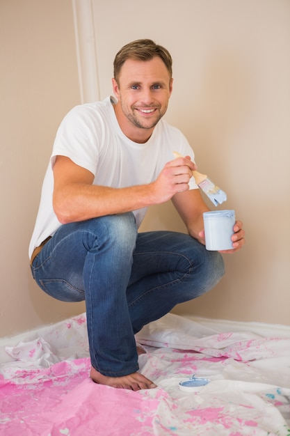 Man using paintbrush to paint wall blue