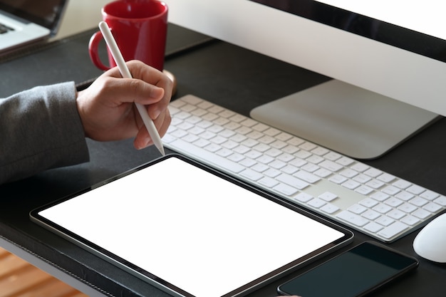 Man using pencil and blank screen tablet on workspace office table