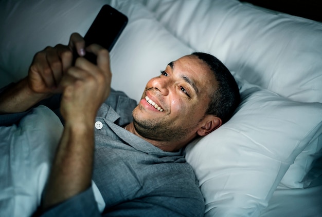 Photo man using phone on a bed