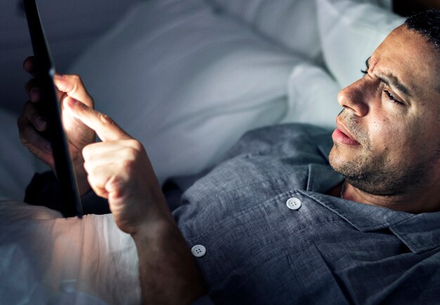 Man using phone on a bed