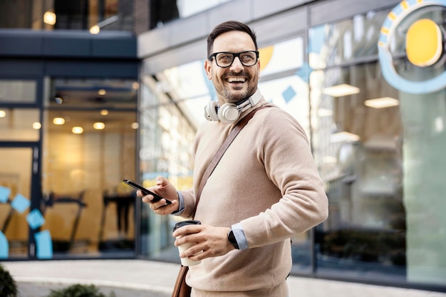 A man using phone and having coffee to go on the street