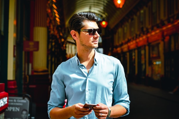 Photo man using phone while standing against buildings in city