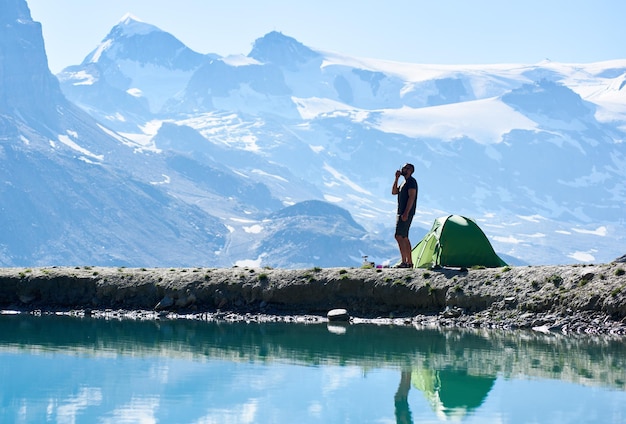 Man using radio near tent in mountains