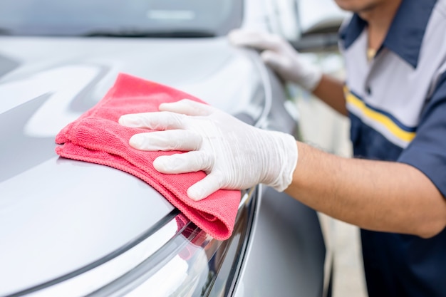 Uomo che per mezzo del panno rosso per pulire l'automobile di suv