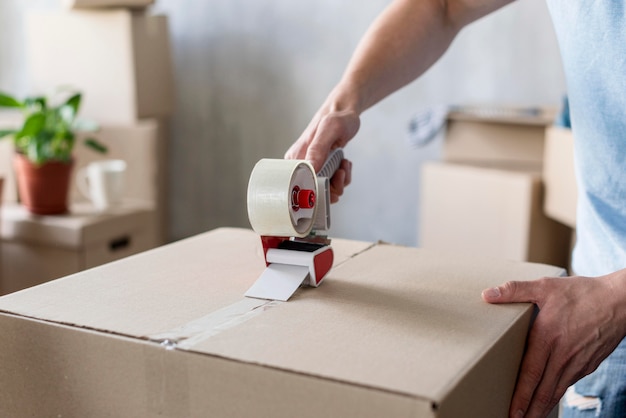 Man using scotch tape on box ready for moving out