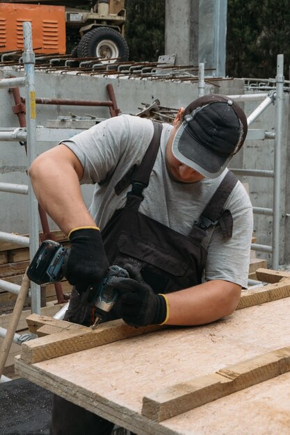 Man using screwdriver while working with wooden materials on construction site