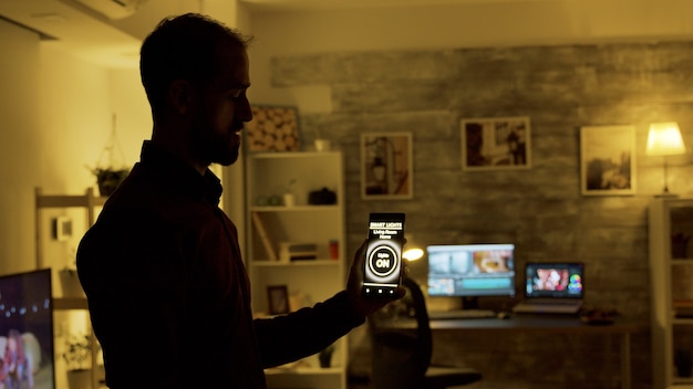 Man using a smart lights application to turn on the light bulbs in the house.