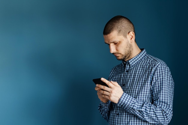 青い背景にスマートフォンを使っている男性