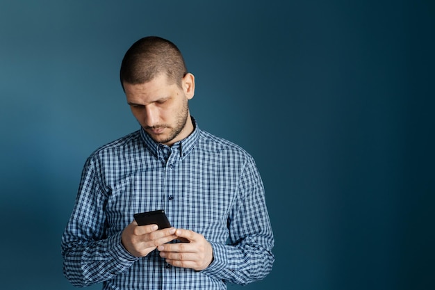 青い背景にスマートフォンを使っている男性