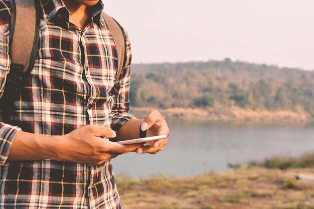 写真 川のそばでスマートフォンを使っている男性