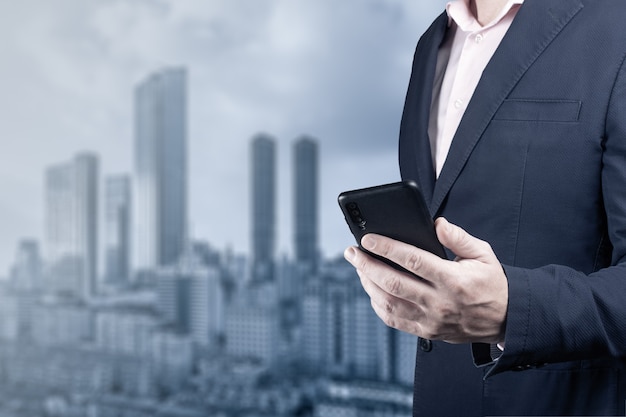 Man using smart phone on  city background background man in suit is holding phone cellular internet