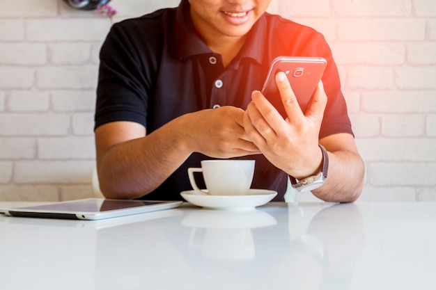 コーヒーショップでスマートフォンを使っている男