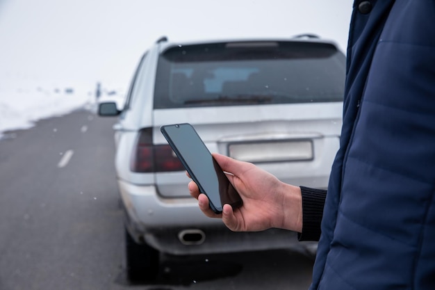 車の背景でスマートフォンを使用している男性