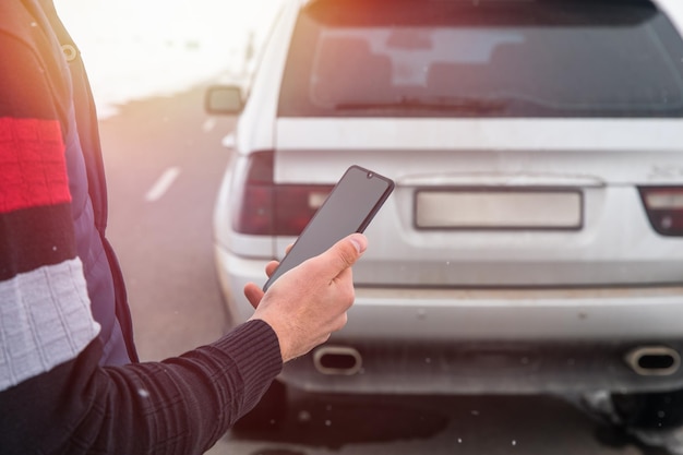 車の背景でスマートフォンを使用している男性