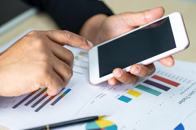 Man using smartphone next to charts and graphs