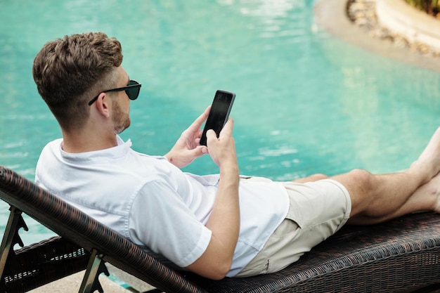 Man using smartphone at outdoor pool