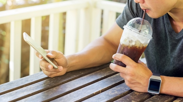 Man using a smartphone and a smartwatch in a coffee shop.