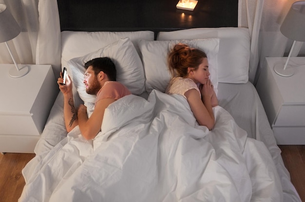 Photo man using smartphone while girlfriend is sleeping