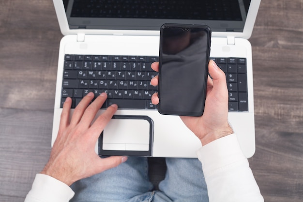 Photo man using smartphone and working on laptop.