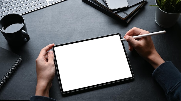 A man using stylus pen and working on digital tablet at his workspace