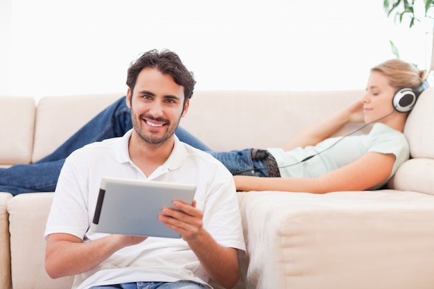 Человек с помощью планшетного компьютера, пока его жена слушает музыку
