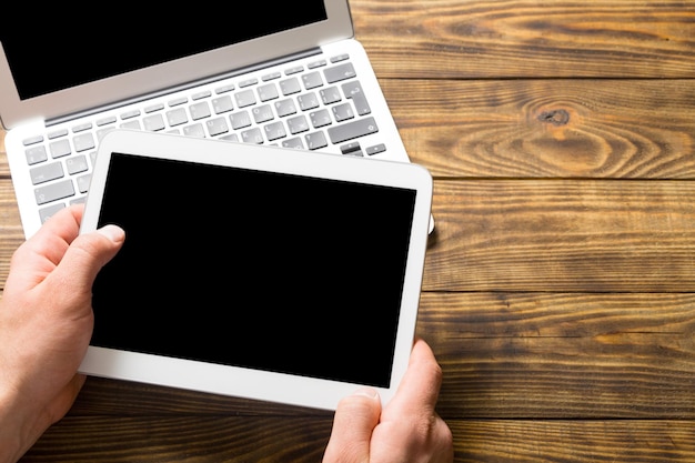 Man using tablet and laptop, laptop on background