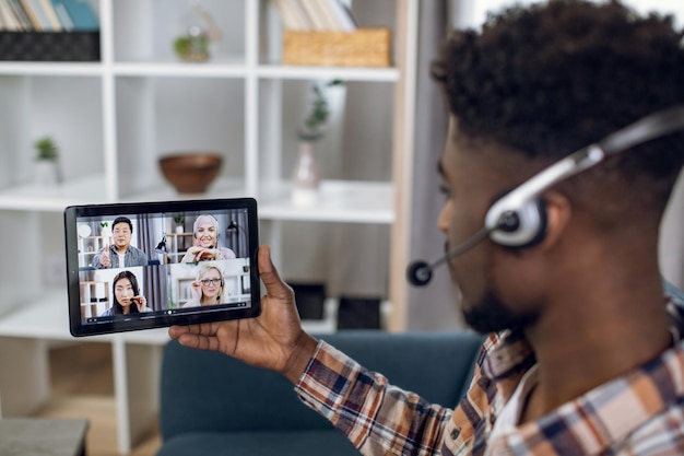 Photo man using tablet for video call with multiracial partners