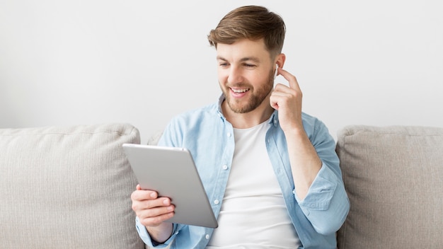 Uomo che per mezzo della compressa e indossando airpods