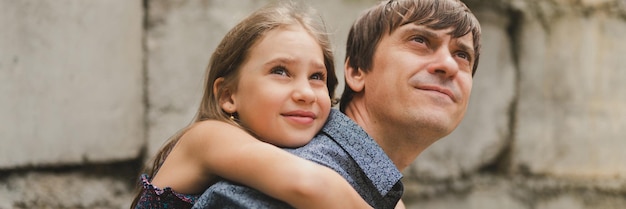 Man vader met quality time met hun kind dochter meisje negen jaar oud op zijn rug gelukkige vader spelen met kind het echte leven authentieke dag van vandaag vaderschap momenten vaderlijke liefde zorg banner