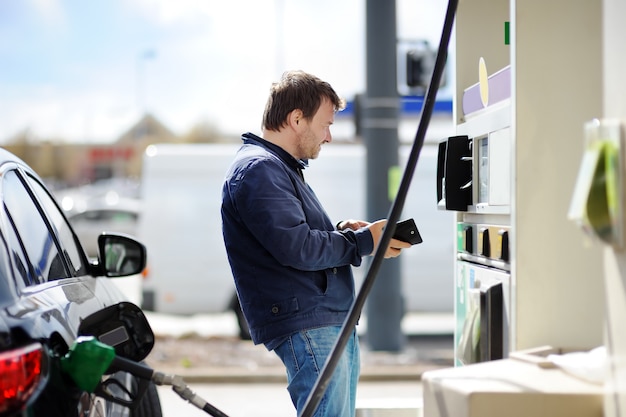 Man van de middenleeftijdsmens het vullen benzinebrandstof in auto