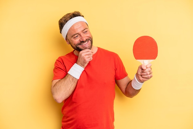 Man van middelbare leeftijd die lacht met een gelukkige, zelfverzekerde uitdrukking met de hand op de kin. pingpongconcept