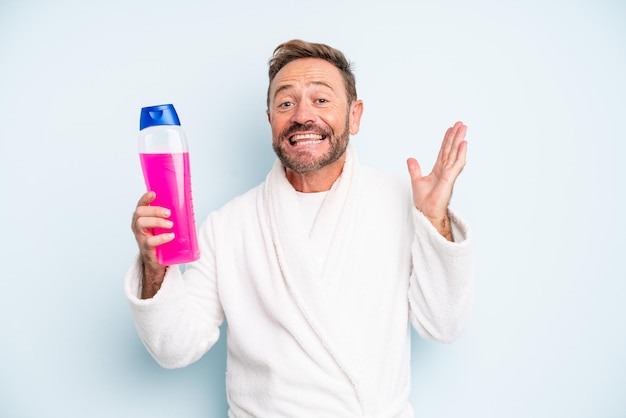 Man van middelbare leeftijd die zich gelukkig en verbaasd voelt over iets ongelooflijks. shampoo fles