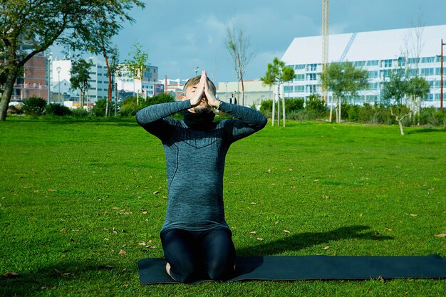 Man van middelbare leeftijd doet ademhaling, ontspanning, yoga, rekken, oefenen, trainen in het park met behulp van yogamat. natuurlijke yoga voor beginners. gezondheidszorg concept.