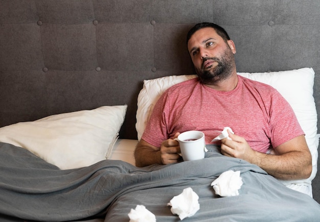 Man van middelbare leeftijd in bed ziek met griepsymptomen.