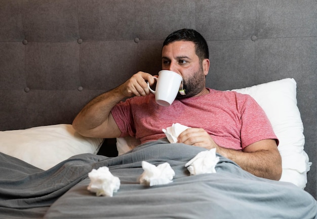 Man van middelbare leeftijd in bed ziek met griepsymptomen.