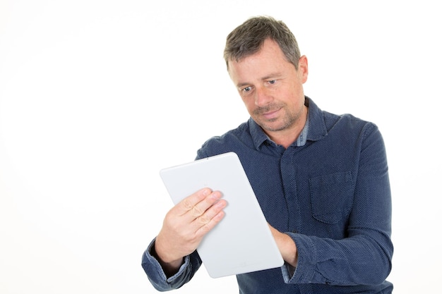 Man van middelbare leeftijd in casual blauw shirt met behulp van tablet pc op witte achtergrond