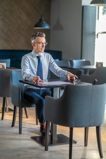 Man van middelbare leeftijd in elegante kleding aan tafel in een café