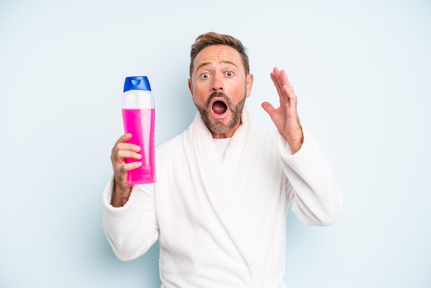 Man van middelbare leeftijd schreeuwen met handen omhoog in de lucht. shampoo fles