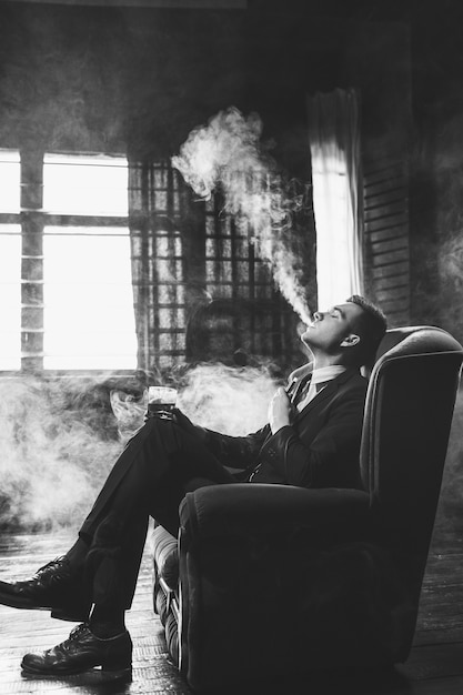 남자 vaping 연기와 술을 마시는 휴식. 즐거움 만족과 냉담한 컨셉