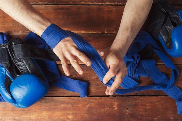 Man verband boksband op zijn handen voor de bokswedstrijd op een houten oppervlak. Het concept van training voor bokstraining of vechten. Plat lag, bovenaanzicht