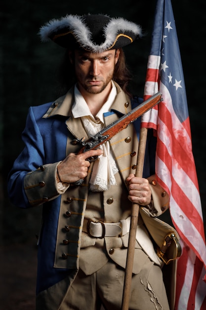 man verkleed als soldaat van War of Independence Verenigde Staten mikt vanuit pistool met vlag