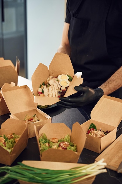 Foto man verpakt voedsel in de papieren eco-dozen binnen restaurant