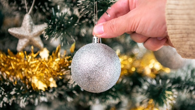 Man versieren kerstboom met zilveren ballen in woonkamer huis. Prettige kerstdagen en gelukkig nieuwjaar concept. Mensen die kerstversieringen op vuren takken zetten. Gezellige familiemomenten